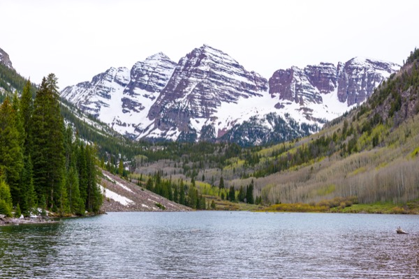 Maroon Bells peaks under a dramatic cloudy sky reflecting in lake at sunset